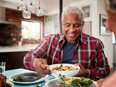 Man smiling while filling plate with food at home