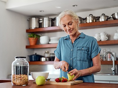 Smiling woman cutting apple in kitchen