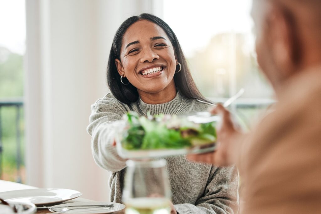 Woman smiling while grabbing salad dish